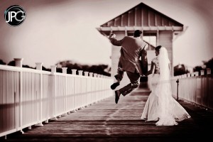 Groom jumps for joy with bride.